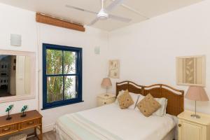 a white bedroom with a bed and a window at Santorini - Pyrgos 15 in Ballito