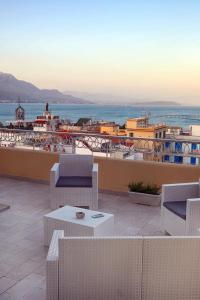 a patio with chairs and a table and the ocean at La terrazza dei colori in Gaeta