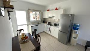 a kitchen with a table and a stainless steel refrigerator at Roof Terrace & Sea View Entire Apartment in Peyia