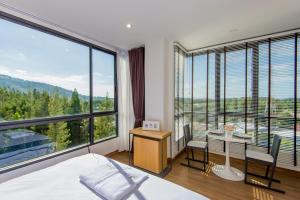 a bedroom with a bed and a desk and a table with chairs at Hill Myna Condotel in Bang Tao Beach