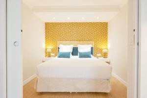 ein Schlafzimmer mit einem großen weißen Bett mit blauen Kissen in der Unterkunft Hôtel Des Batignolles in Paris