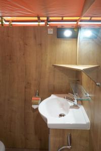 La salle de bains est pourvue d'un lavabo blanc et de murs en bois. dans l'établissement Cabane Ayana, à Saint-Maximin-la-Sainte-Baume