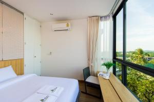 a bedroom with a bed and a large window at Hill Myna Condotel in Bang Tao Beach