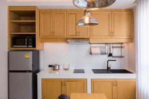 a kitchen with wooden cabinets and a stainless steel refrigerator at Aurico Kata Resort & Spa - SHA Extra Plus in Kata Beach