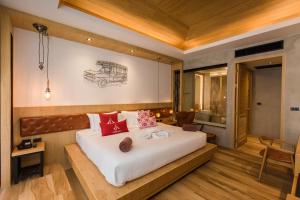 a bedroom with a large white bed with red pillows at Aurico Kata Resort & Spa - SHA Extra Plus in Kata Beach