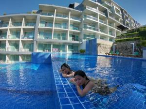 カタビーチにあるSugar Palm Grand Hillside - SHA Plusのホテルのプールで泳ぐ女の子2名