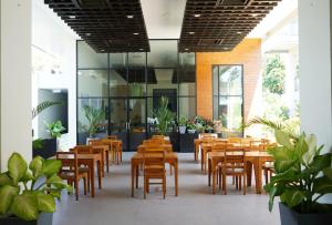 a restaurant with wooden tables and chairs and plants at Sugar Palm Grand Hillside - SHA Plus in Kata Beach