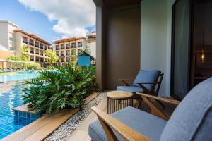 a resort balcony with chairs and a swimming pool at Aurico Kata Resort & Spa - SHA Extra Plus in Kata Beach