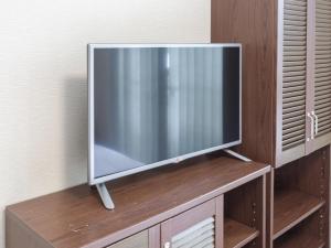 TV de pantalla plana en la parte superior de un armario de madera en Tabist International Hotel Kaike, en Yonago