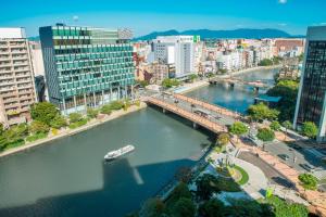 einen Fluss in einer Stadt mit einem Boot im Wasser in der Unterkunft mizuka Imaizumi 1 - unmanned hotel - in Fukuoka