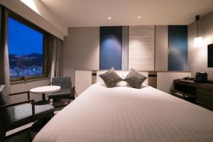 長崎市にあるホテルJALシティ長崎のベッドとデスクが備わるホテルルームです。