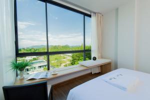 Hill Myna Condotel في شاطئ بانغ تاو: غرفة نوم بسرير ونافذة كبيرة