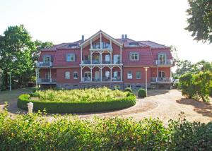 a large red house with a garden in front of it at Villa Seegarten in Boltenhagen