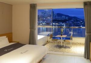 a hotel room with a bed and a large window at Lium Spa Hostel in Yeosu