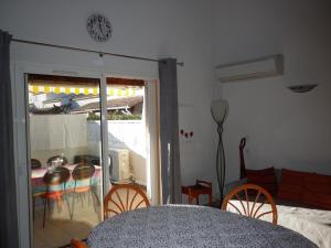 a living room with a table and chairs and a clock at Les Andalouses in Cap d'Agde