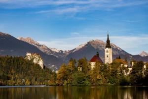 a church on a lake with mountains in the background at APARTMA JANŠA in Bled