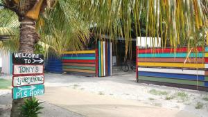 バトゥ・フェリンギにあるTony’s Guesthouse at Teluk Bahangの椰子の木の隣の看板のあるカラフルな建物