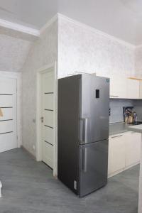 a stainless steel refrigerator in a kitchen with white cabinets at Золотой Бугаз in Gribovka