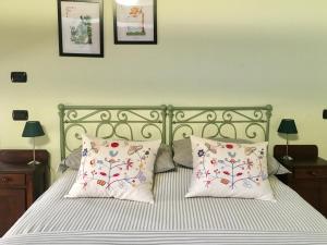 a bed with two pillows and two pictures on the wall at Cascina Bertolotto Wine Resort in Spigno Monferrato