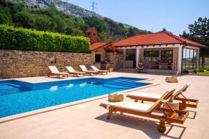a swimming pool with lounge chairs and a house at Villa Delmati in Tugare
