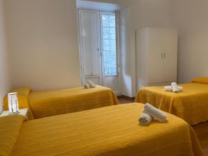 three beds in a room with yellow sheets at Pensión Hedrass in Santiago de Compostela