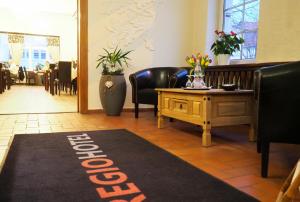 a restaurant with a table and chairs and a welcome rug at REGIOHOTEL Quedlinburger Hof Quedlinburg in Quedlinburg