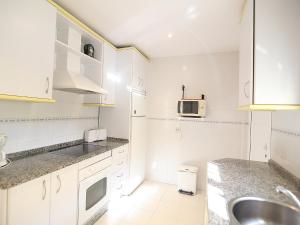 a white kitchen with a sink and a microwave at Holiday Home Brisamar - Novo Sancti Petri by Interhome in Chiclana de la Frontera