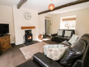 a living room with a leather couch and a fireplace at The Cottage Glossop in Glossop