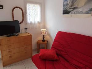 a bedroom with a red bed and a dresser with a television at Holiday Home Les Capellanes by Interhome in Saint-Cyprien-Plage