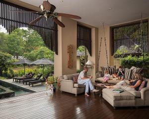 a family sitting on couches in a living room at Four Seasons Resort Chiang Mai -SHA Plus in Mae Rim