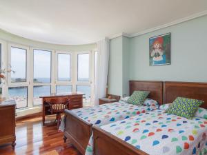 a bedroom with a bed and a desk and windows at Apartment Rico by Interhome in Castro-Urdiales