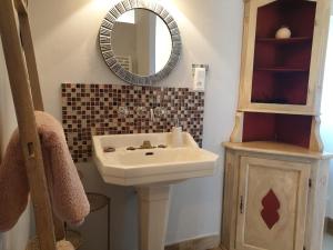 La salle de bains est pourvue d'un lavabo et d'un miroir. dans l'établissement Chambre d'hôtes de la Bigottière, à Madré