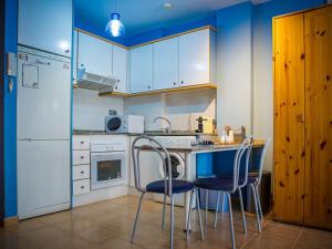 カネット・デ・ベレンゲルにあるApartment Segrelles by Interhomeの青い壁と白いキャビネット、テーブルと椅子が備わるキッチン