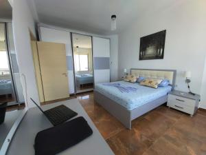 1 dormitorio con 1 cama y escritorio con ordenador portátil en Two Worlds Sea View Apartment, en Sarandë