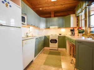 a green kitchen with white appliances and green cabinets at Holiday Home Kallionnenä by Interhome in Mäkikylä