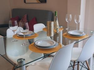 una mesa de cristal con platos y copas de vino. en Apartamentos Centro Emérita, en Mérida