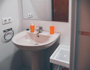 Un baño con lavabo con dos tazas de naranja. en Apartamentos Centro Emérita, en Mérida