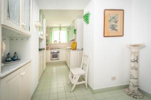 a kitchen with white cabinets and a chair in it at Charming Villa in Capri