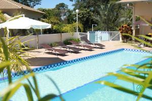 a swimming pool with chairs and an umbrella at PISSIN POUSADA E HOTEL in Marília