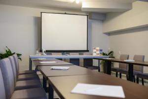 una classe con tavoli, sedie e schermo bianco di Garni Hotel Mediteraneo a Novi Sad