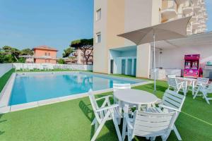 een patio met een tafel en stoelen en een zwembad bij Hotel Adler in Lido di Classe