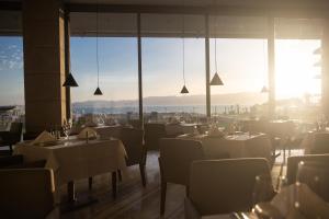 a restaurant with white tables and chairs and windows at ON'LIVE HOTEL in Çeşme