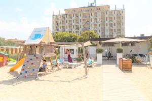 een speeltuin in het zand met een glijbaan en een gebouw bij Hotel Adler in Lido di Classe