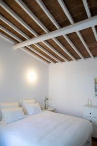 a white bed in a room with a wooden ceiling at Casa da Travessa in Évora