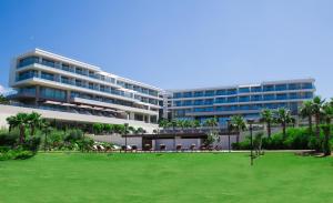 a large building with a green lawn in front of it at ON'LIVE HOTEL in Çeşme