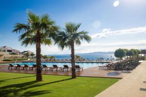 a pool with chairs and palm trees next to the water at ON'LIVE HOTEL in Çeşme