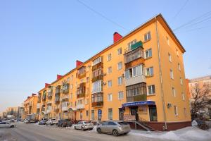 un edificio naranja en una calle con coches aparcados en Omsk Sutki Apartments at Pushkina 99 floor 4 en Omsk