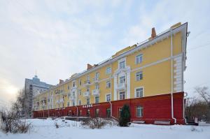 オムスクにあるApartment Karla Marksa 22の雪中の大きな黄色と赤の建物