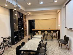 a classroom with tables and chairs and a projection screen at Heyyo Hostel in Hualien City