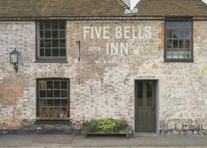 a brick building with a sign that reads five balls dip inn at The Five Bells Inn in Brabourne